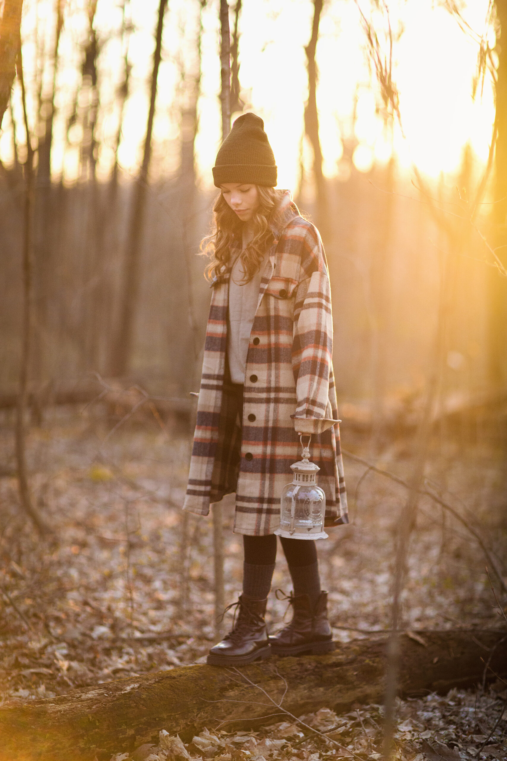 Model walking on log in woods at sundown.